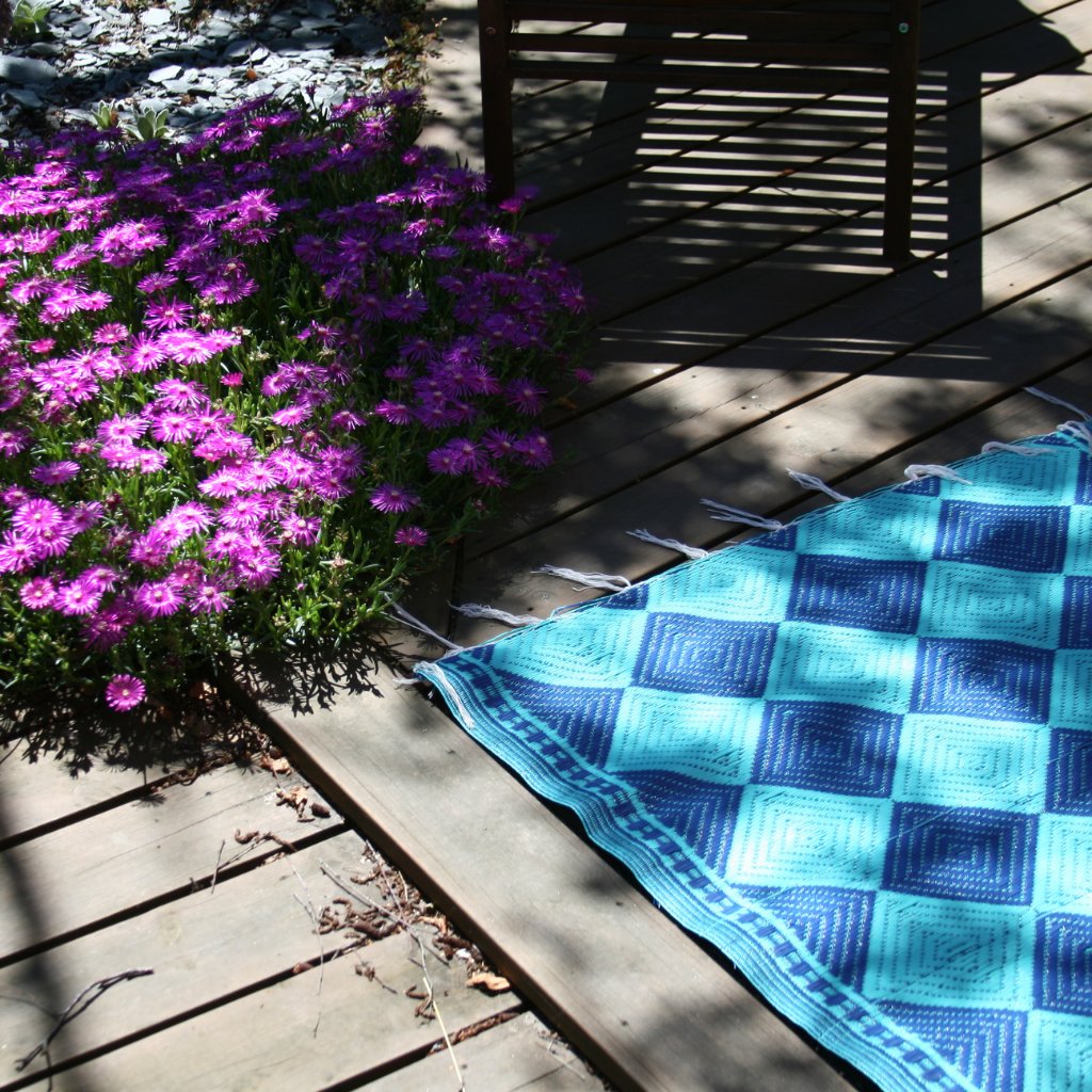 tapis africains en plastique recyclé aux motifs géométriques, des losanges bleu fonçés et bleu turquoise. C'est un damier de losanges