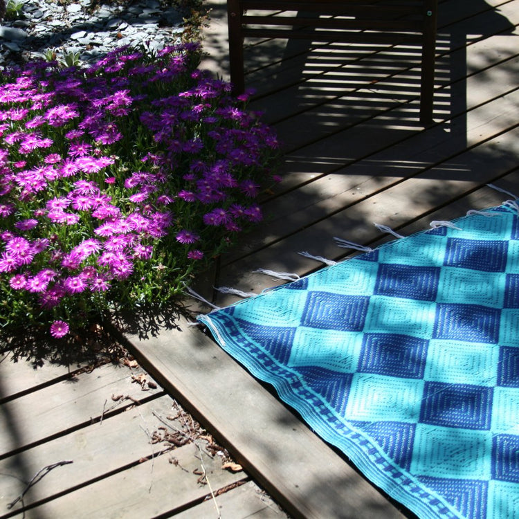 tapis africains en plastique recyclé aux motifs géométriques, des losanges bleu fonçés et bleu turquoise. C'est un damier de losanges